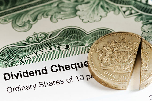 The image is of a UK share dividend with a sliced pound coin laying on top of it.