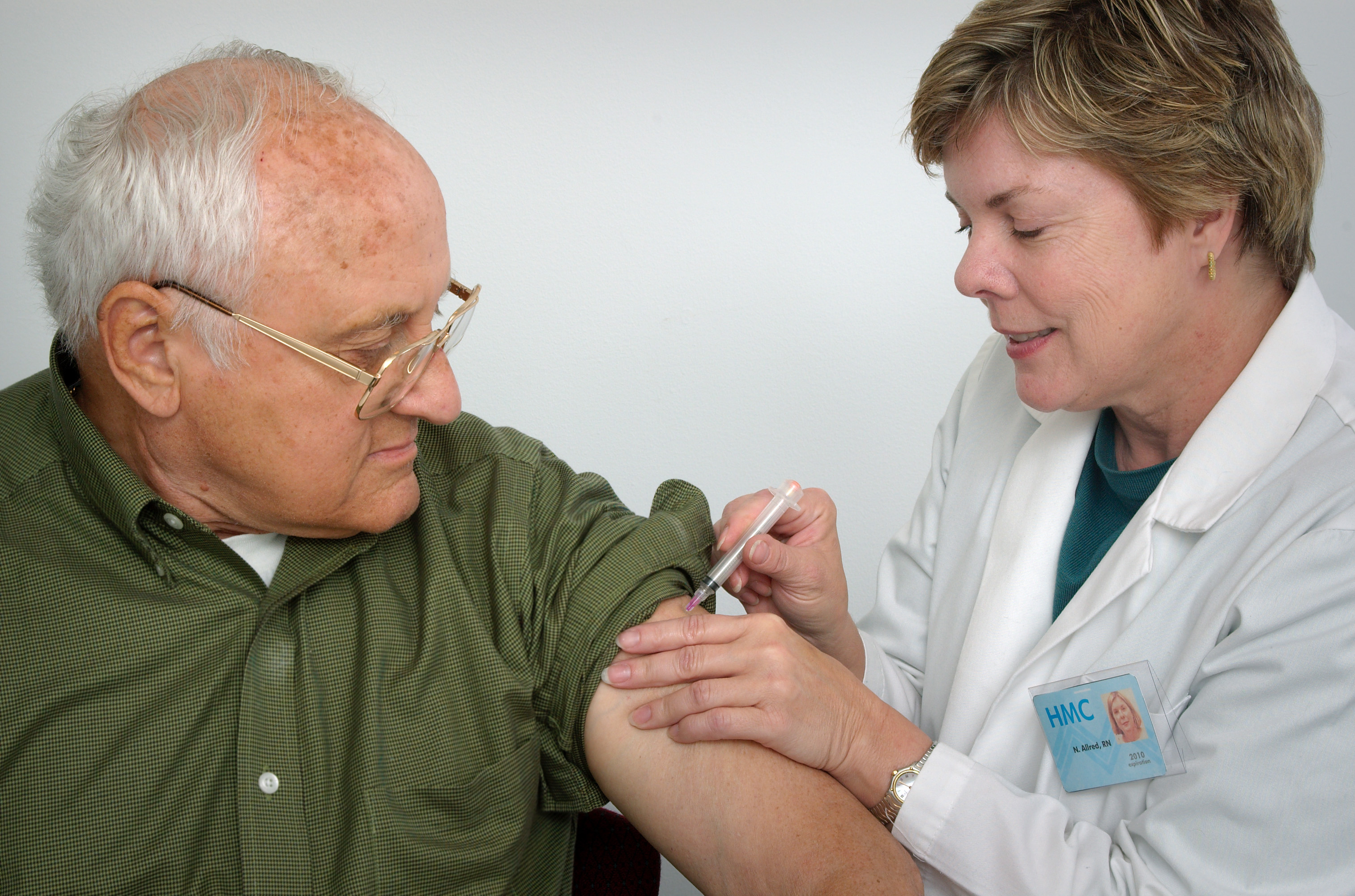 A nurse giving an older man a vaccination shot