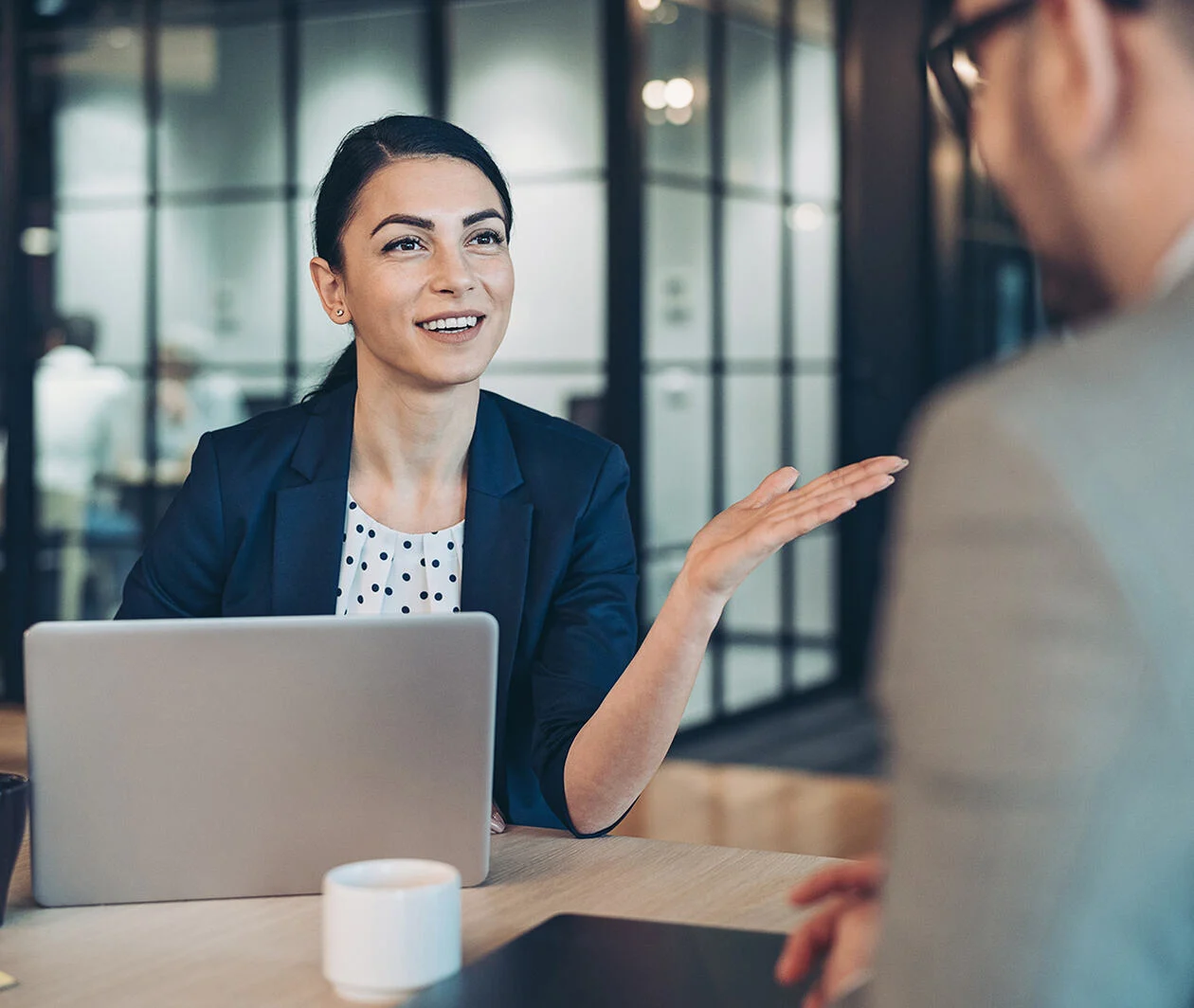 Business woman talking to her client on a desk with computer with confident.