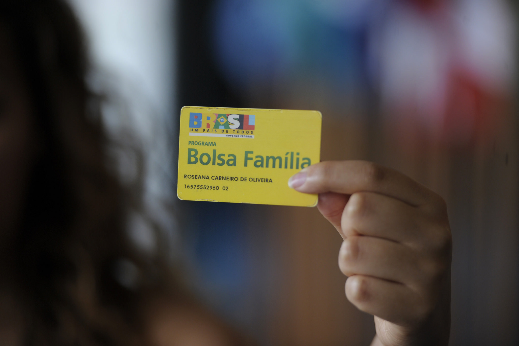 Woman's hand holding Bolsa Familia card