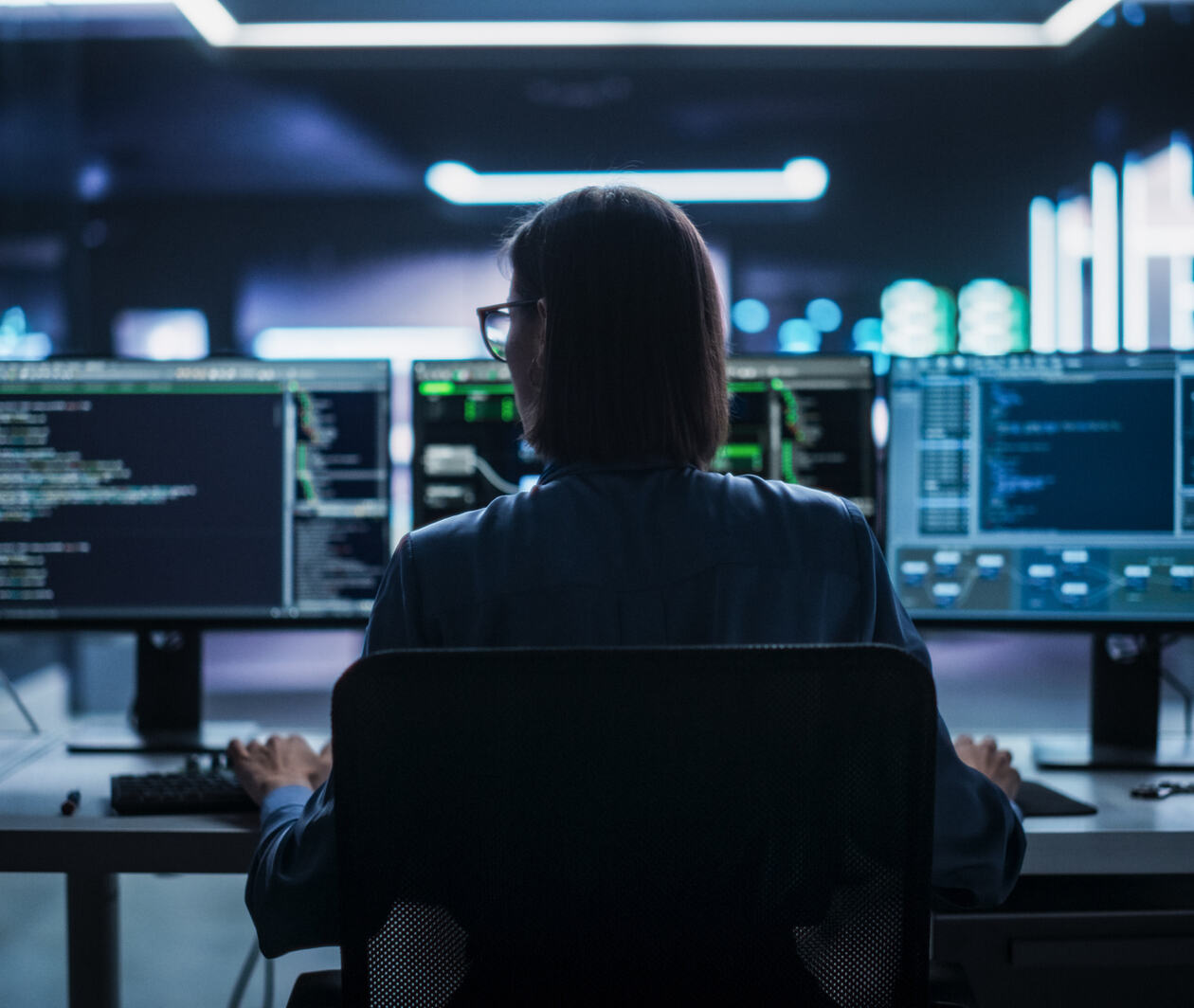 Looking at a woman from the back who is looking at her computer screens