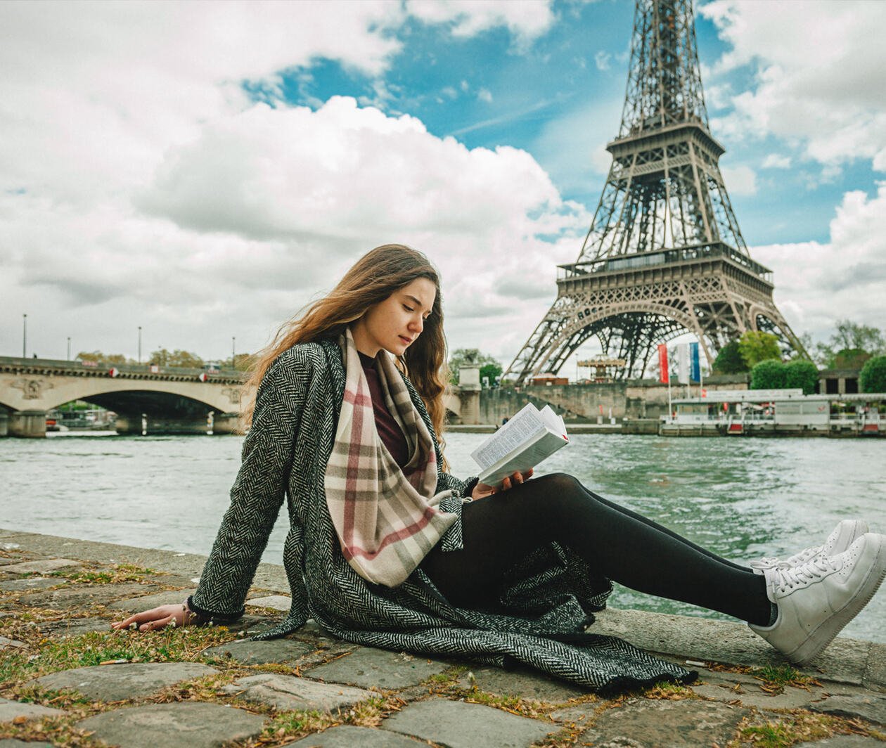 Girl reading poetry in front of the Eiffel Tower