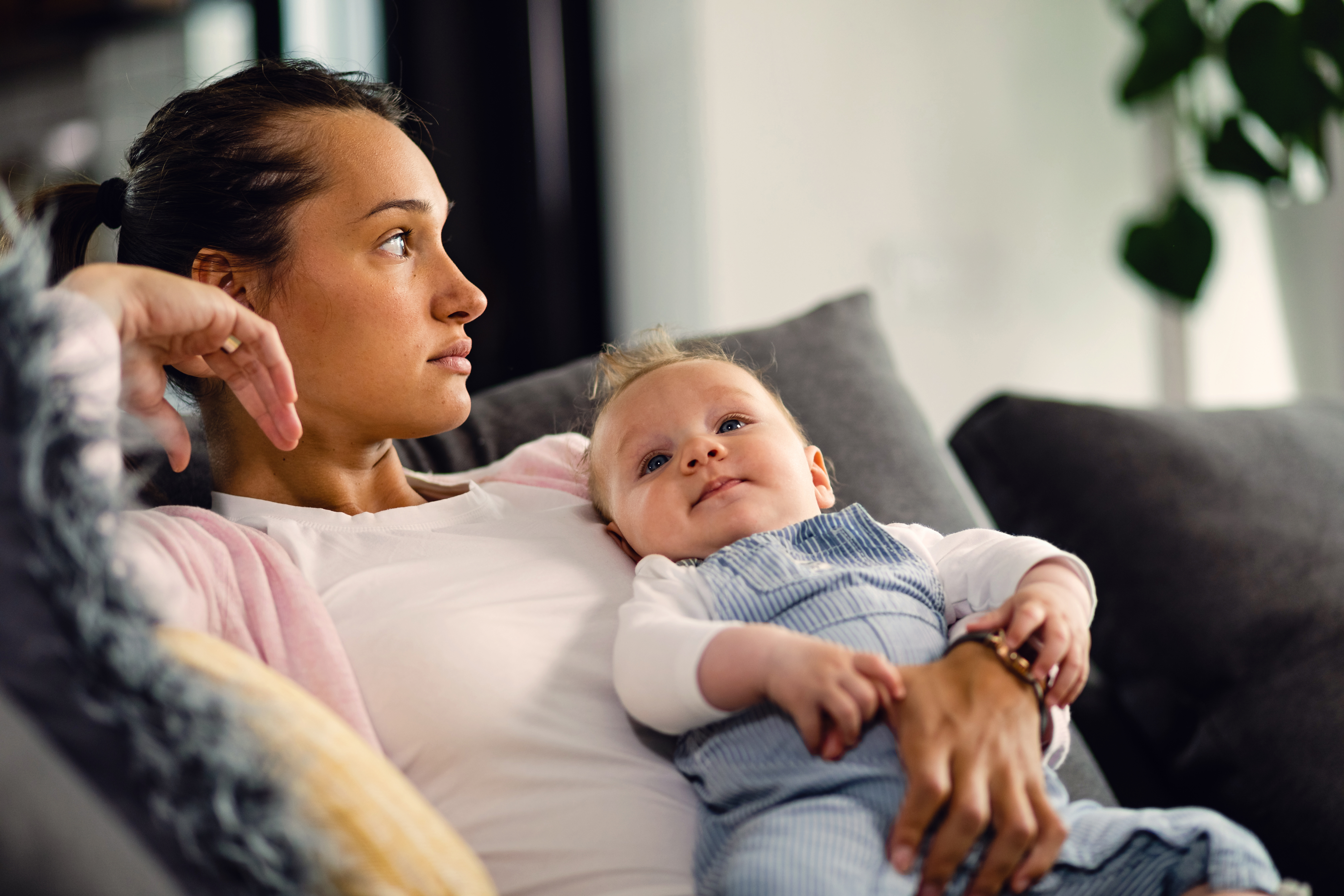 A woman looking into the distance while holding her baby.