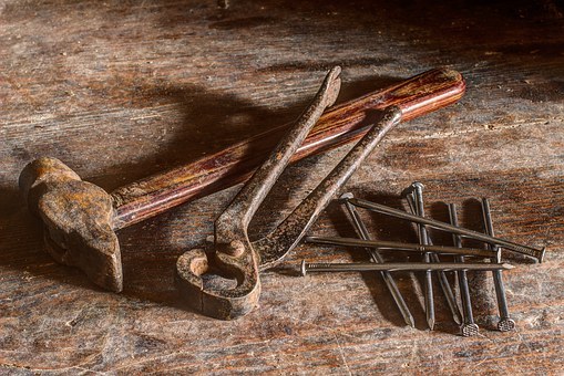 Workshop tools, including a hammer and nails, on a wooden worktop.