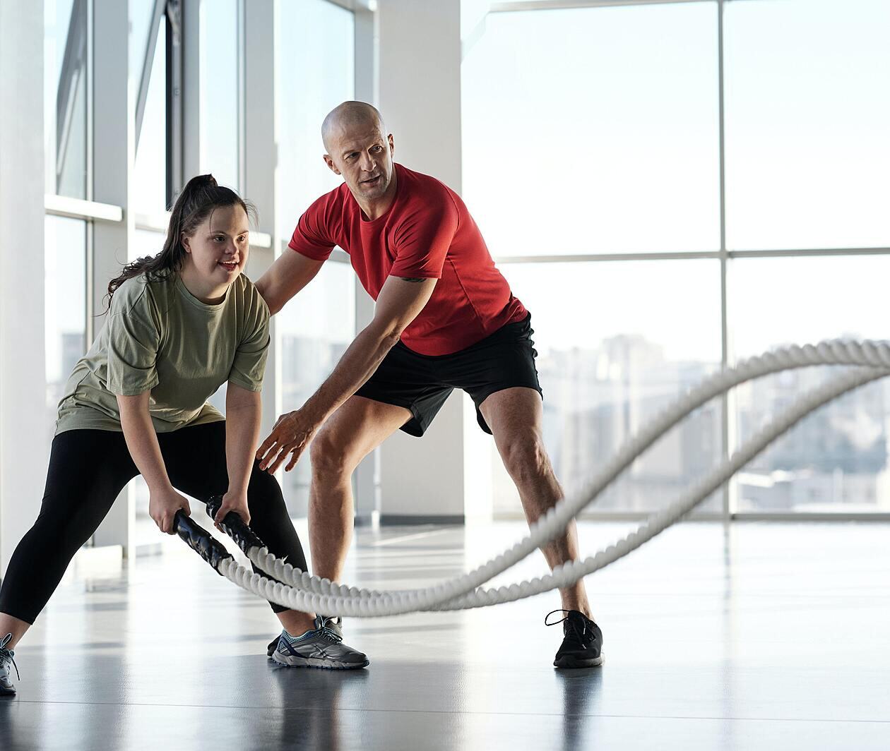 A woman training with ropes whilst a man supports and views her form