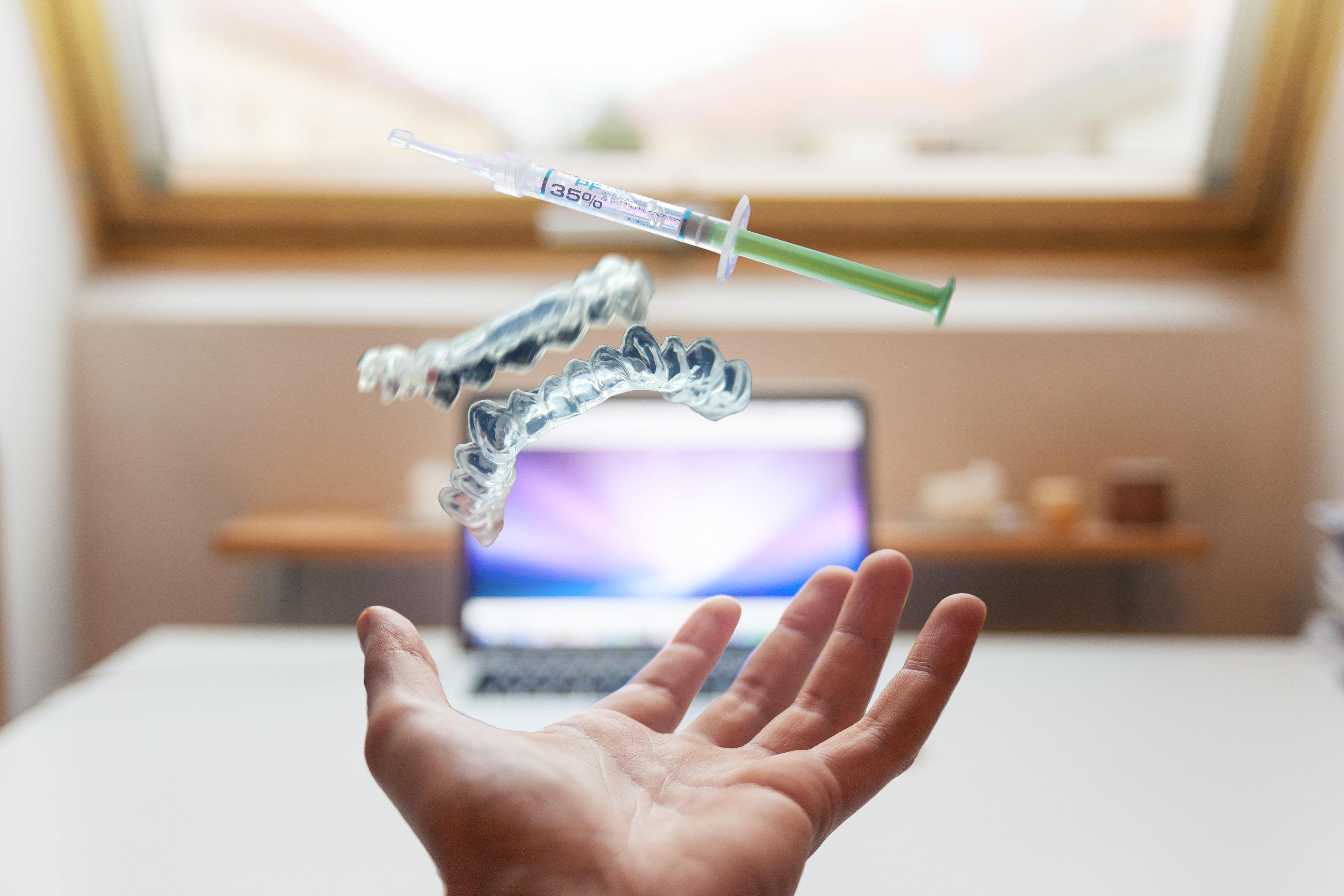 Medical professional sits in front of computer. Above her hand hand virtual anatomical models and syringes hang in the air