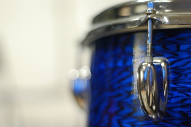 Close up of a blue drum against a blurred white background.