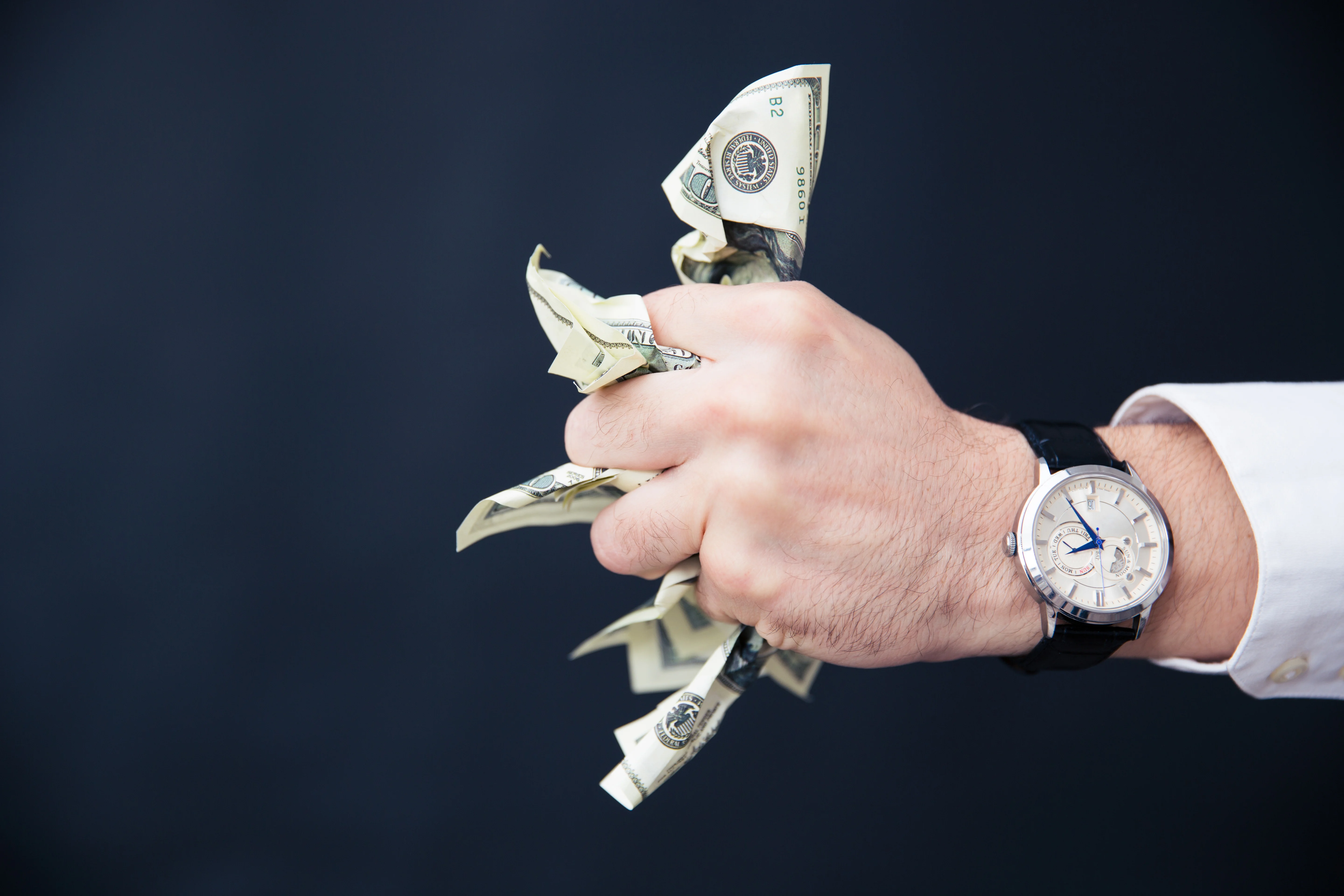 Businessman hand holding bills of US dollar in fist