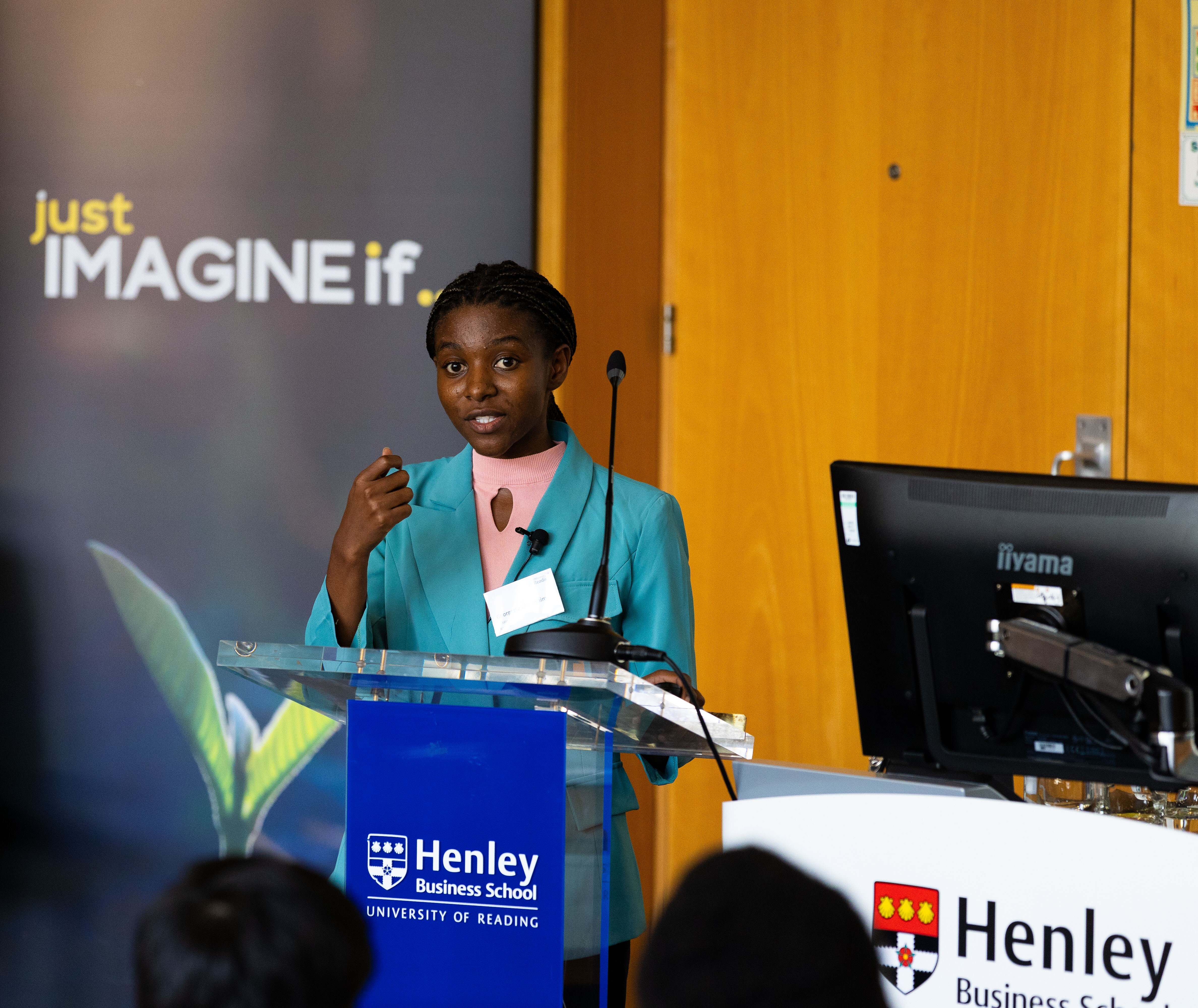 Woman presenting at a podium with the words 'Just imagine if...' behind her