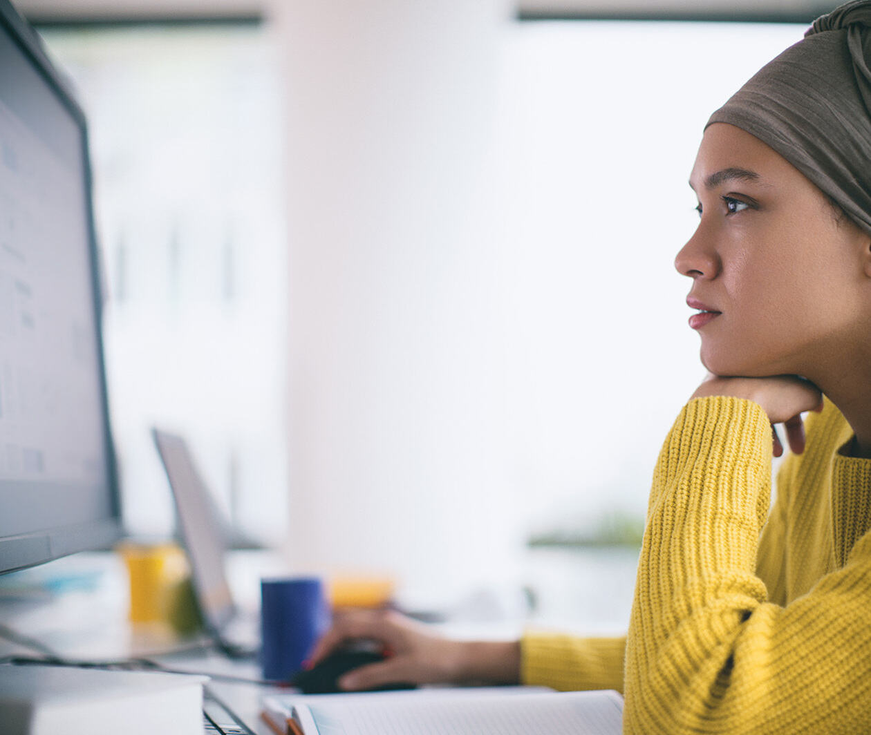 A woman sits on her computer scrolling the mouse. 