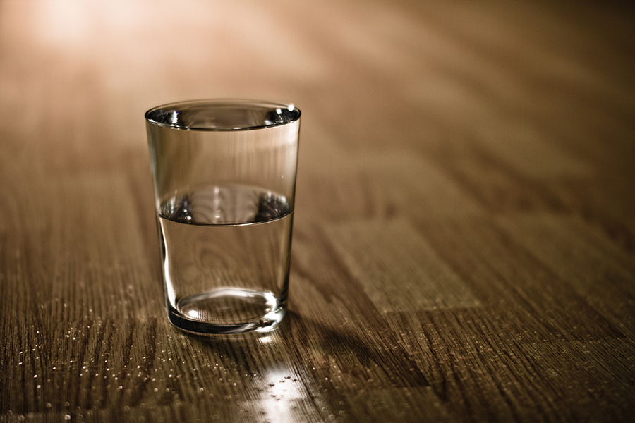 Half-filled glass of water on table.