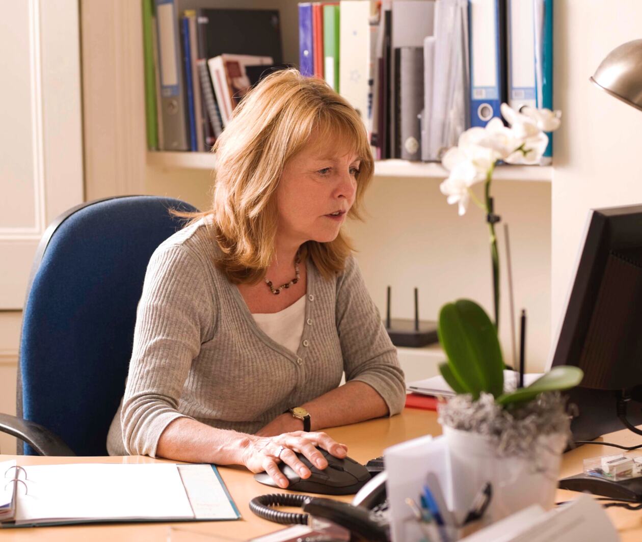 A business woman is busy working on a computer with the mouse in her office.