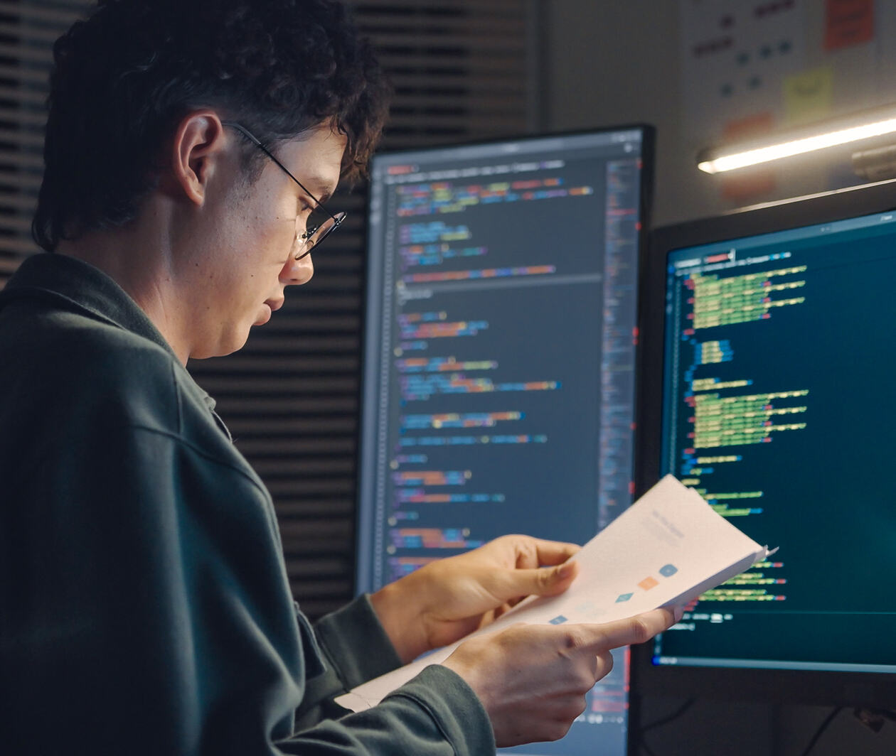 IT specialist software developer working on code examining design based on the visual charts diagrams and design wireframes integrating and development on dual monitors computer
