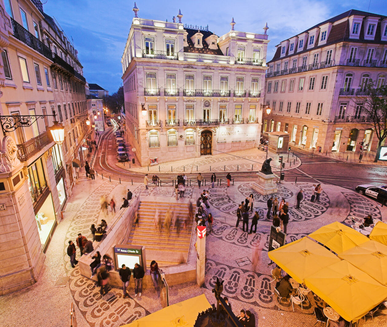 A square in Lisbon, Portgual with stairs down to the subway, people and cafe tables