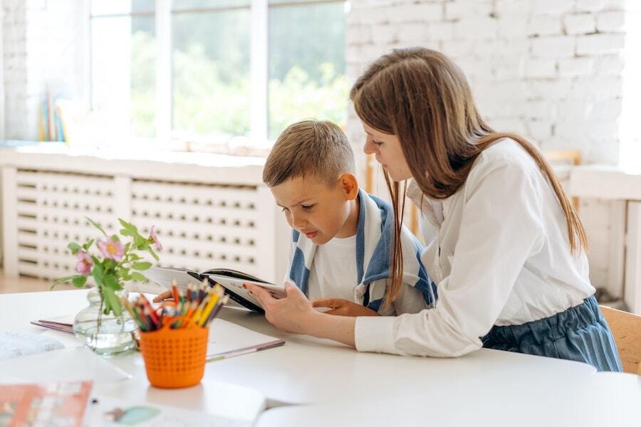 Young kid reading with guidance from his teacher