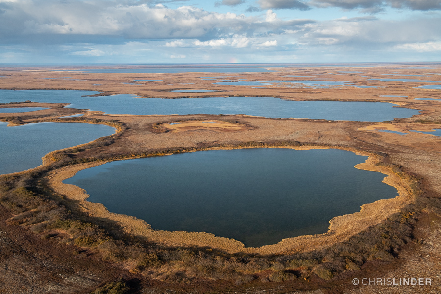 An aerial view of large, dark blue lakes on the orangey-brown Alaskan tundra.