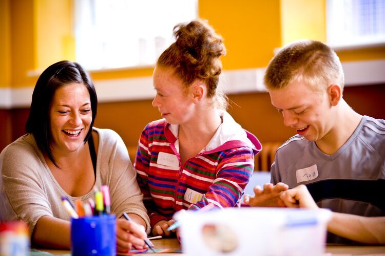 Two secondary school students and a teacher working on a task in a team