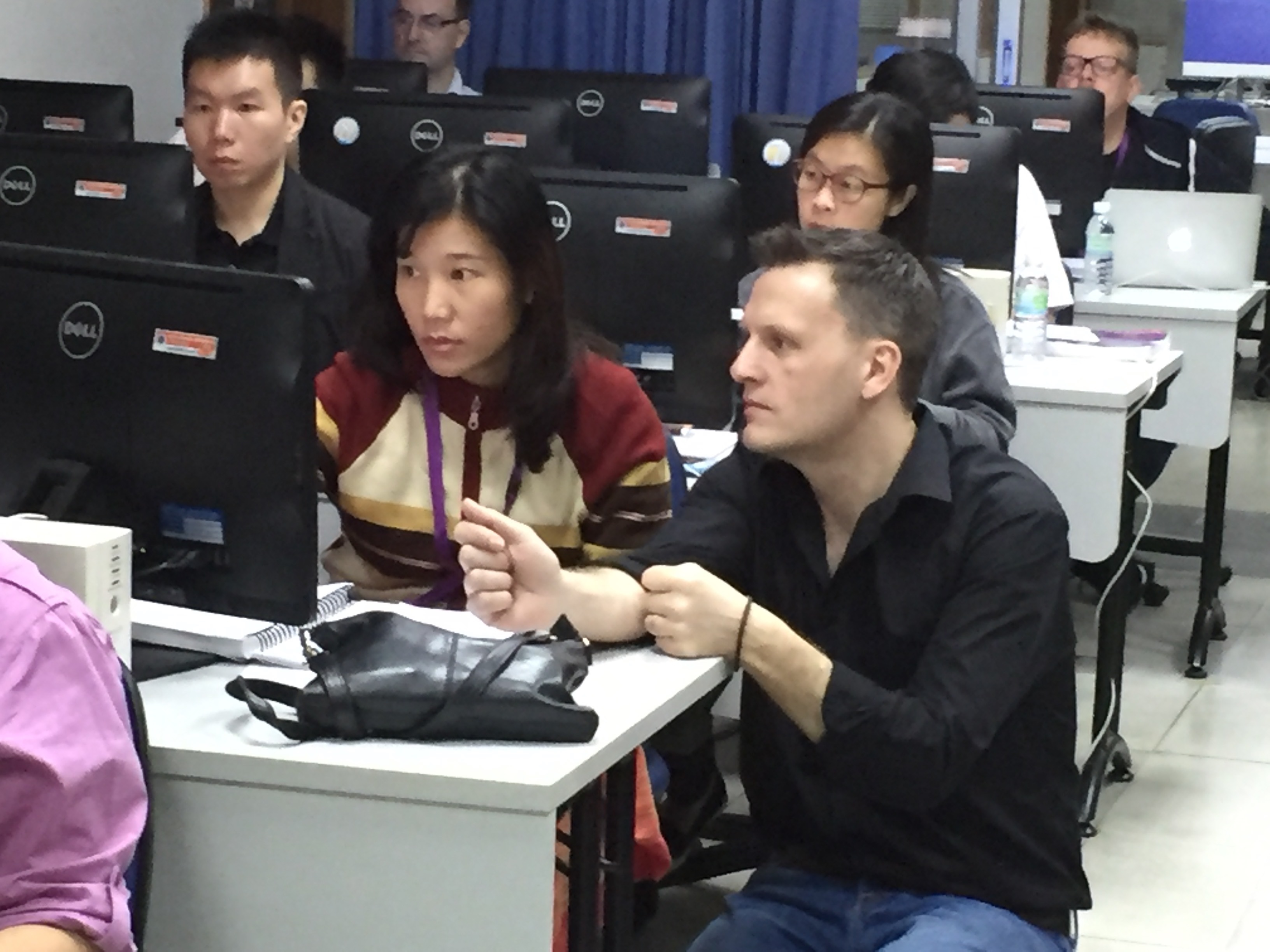 Seated learners at their computers and an Educator by the side of and assisting one learner, in a  computer room