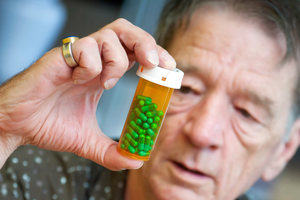 Poster for The science of medicines - a gentleman studies a bottle of green pills