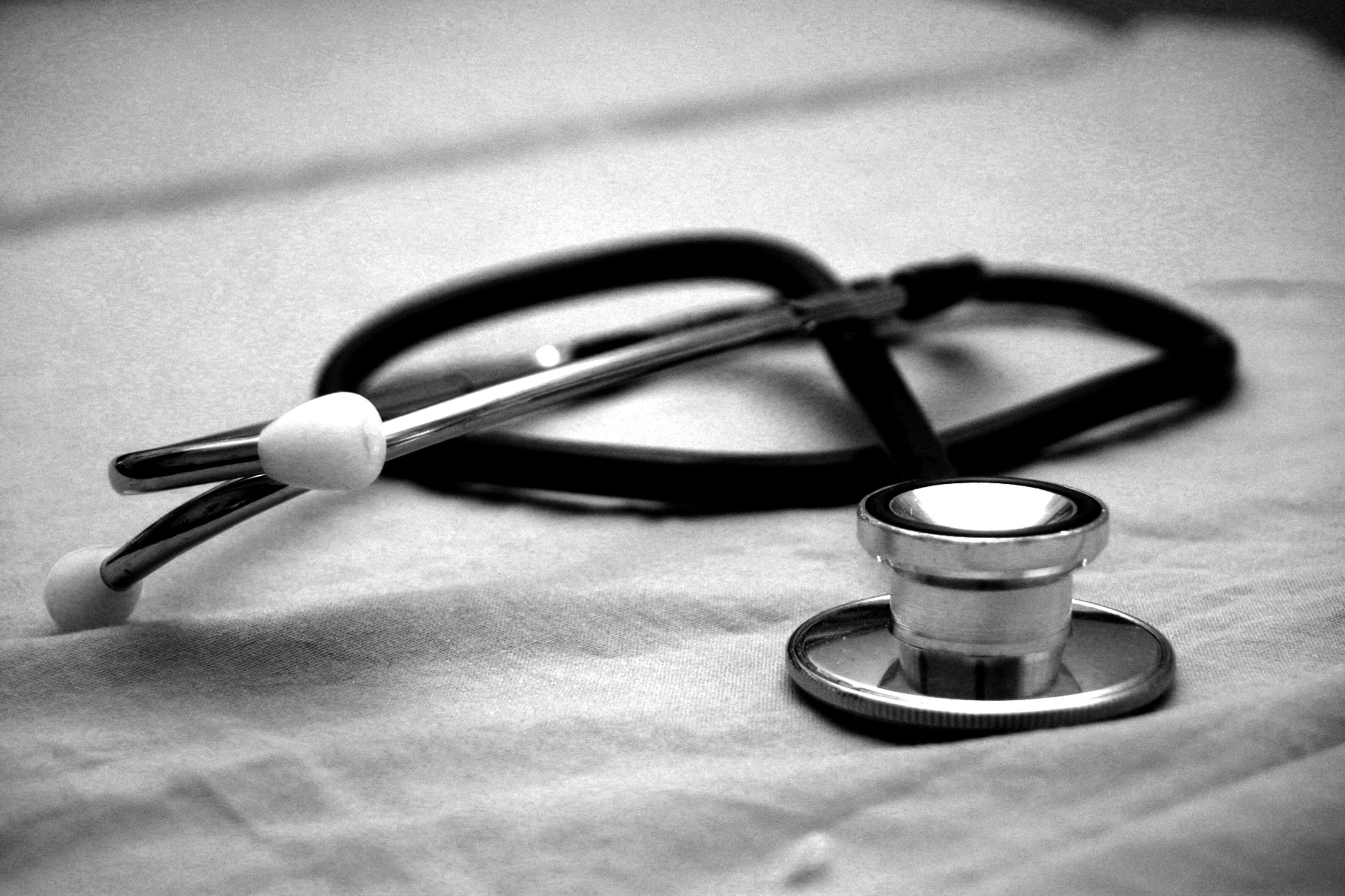 black and white Stethoscope on bed sheets