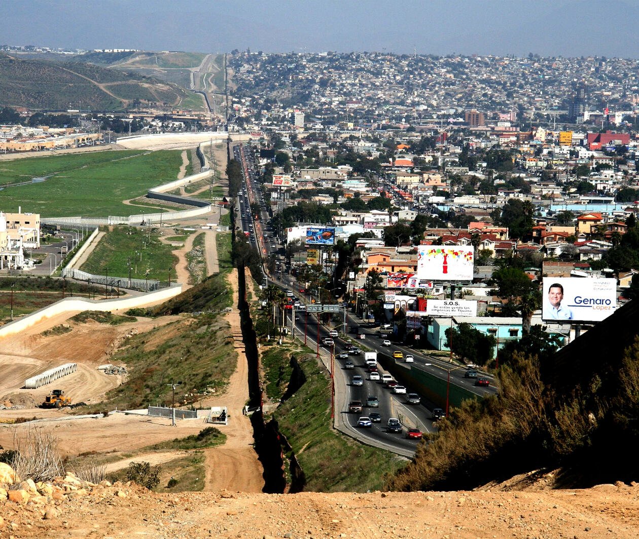 Dense city on the right meets agriculture on the left, with a distinct split down the centre from a border wall.