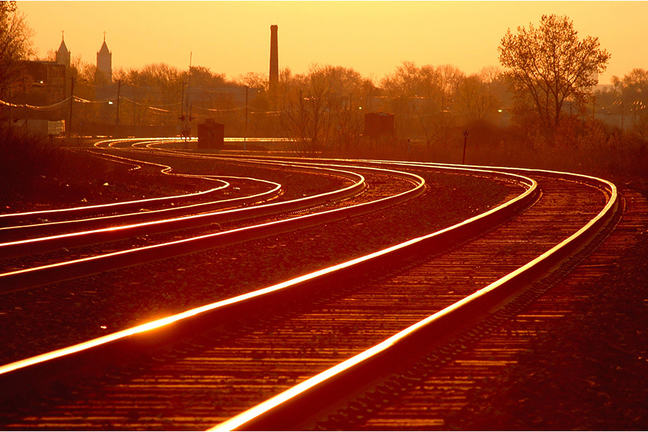 Image is of a train track at sunset.