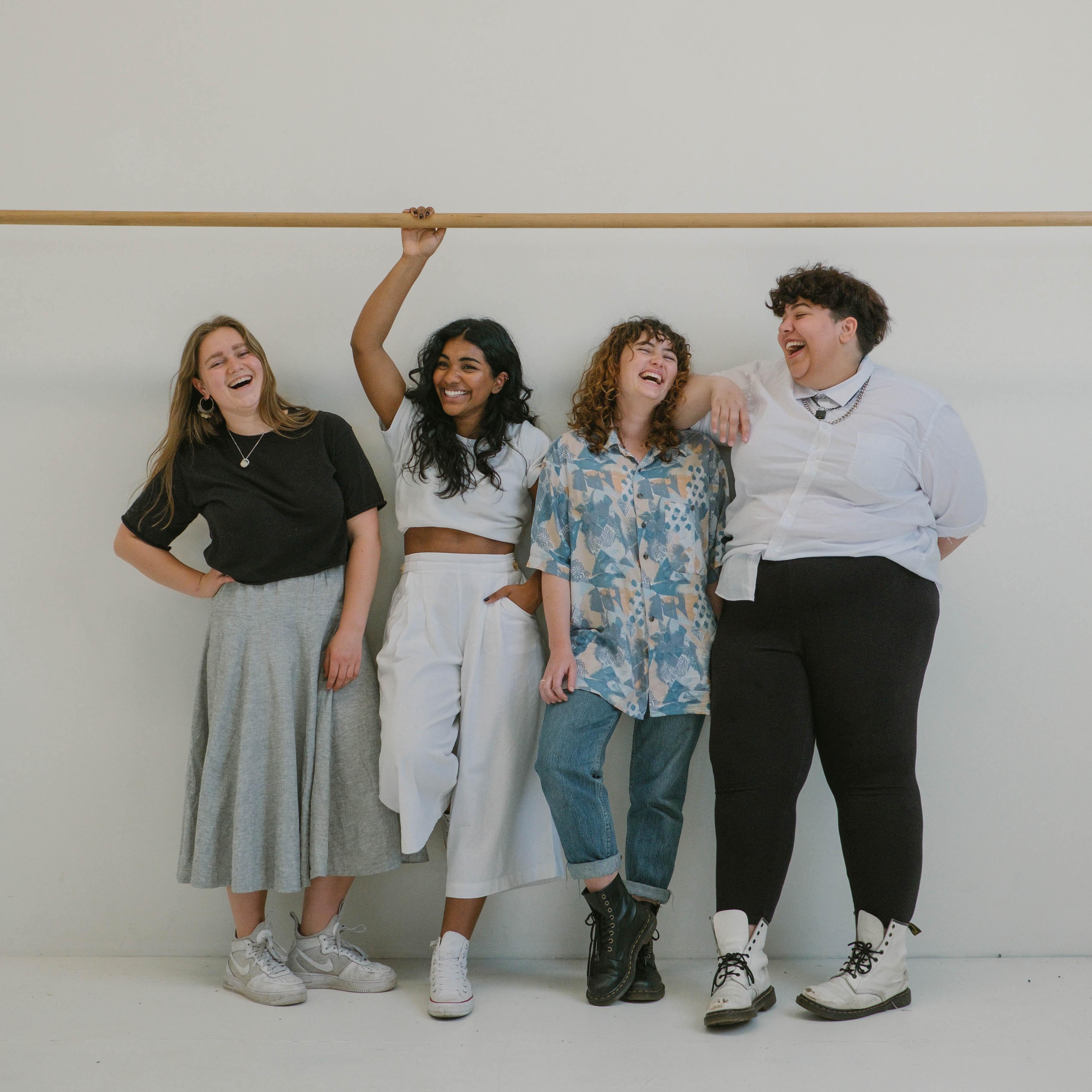 Four people standing beside a wall laughing.