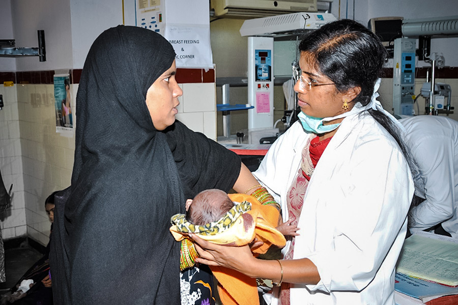 Ophthalmologist and mother standing close together in a clinic with the baby between them