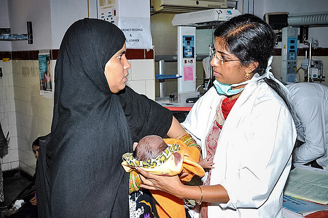 Ophthalmologist and mother standing close together in a clinic with the baby between them