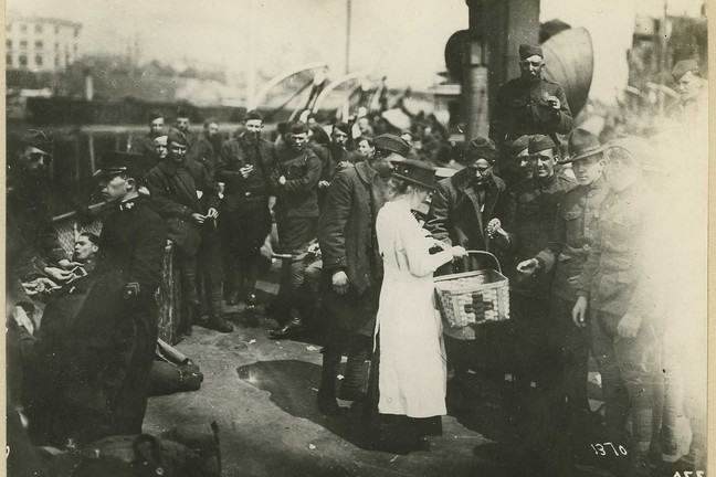 Image of female medical worker offering supplies to sick and wounded soldiers
