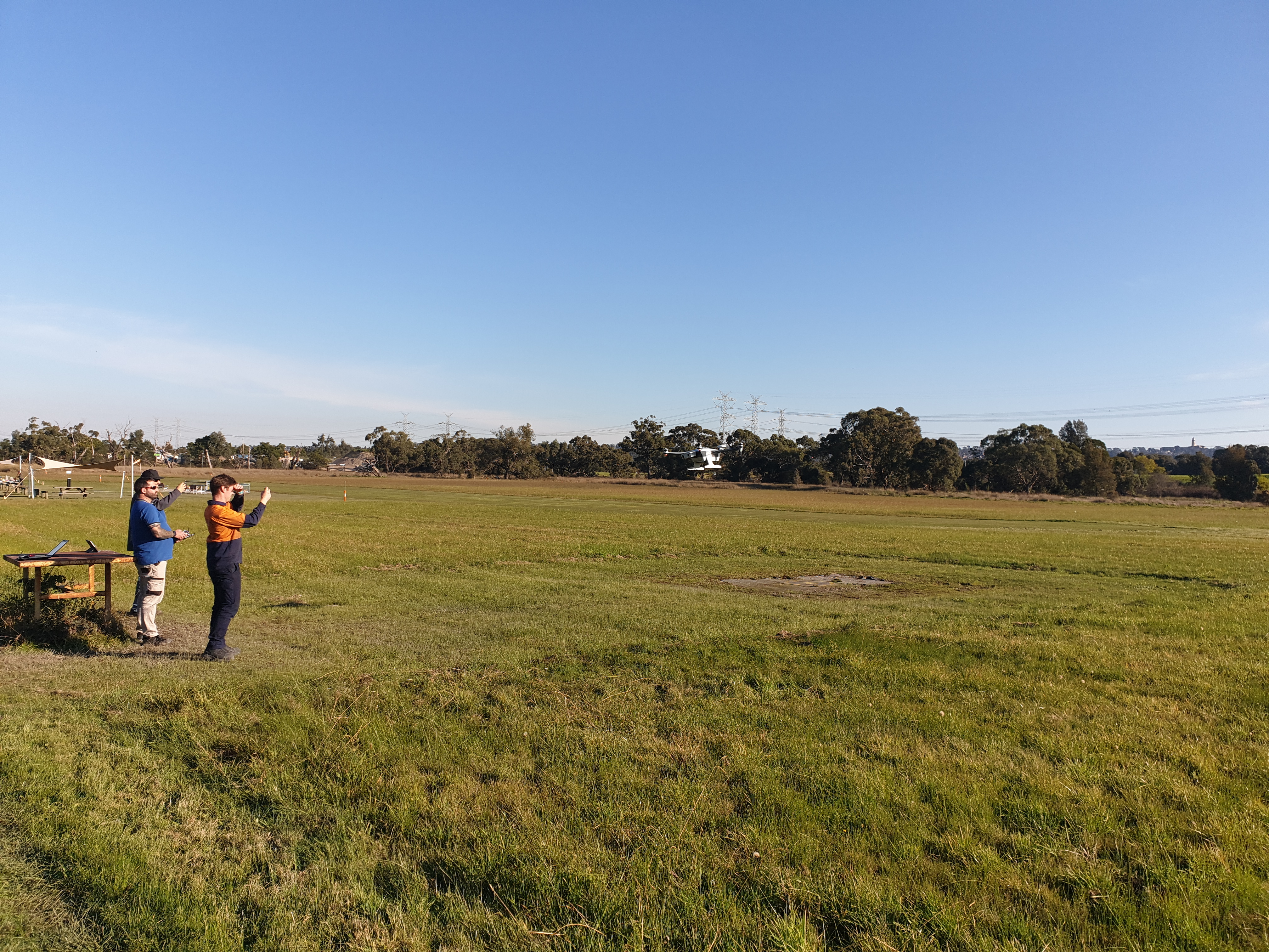 A person being trained to operate a drone in a wide field.