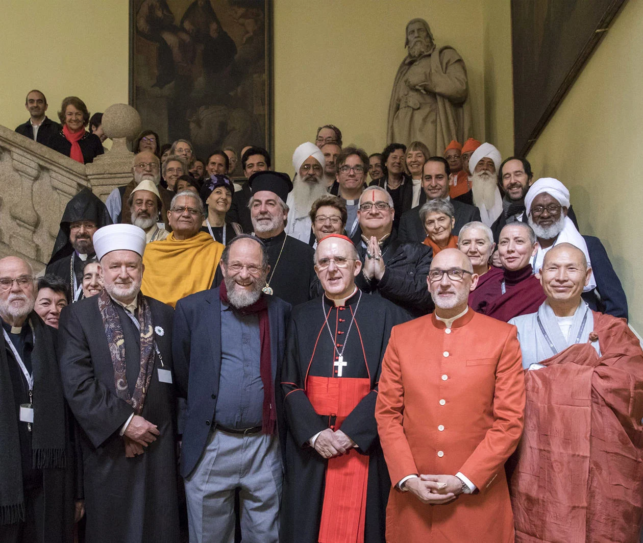 A group of religious leaders from around the world smiling and standing together for a photograph