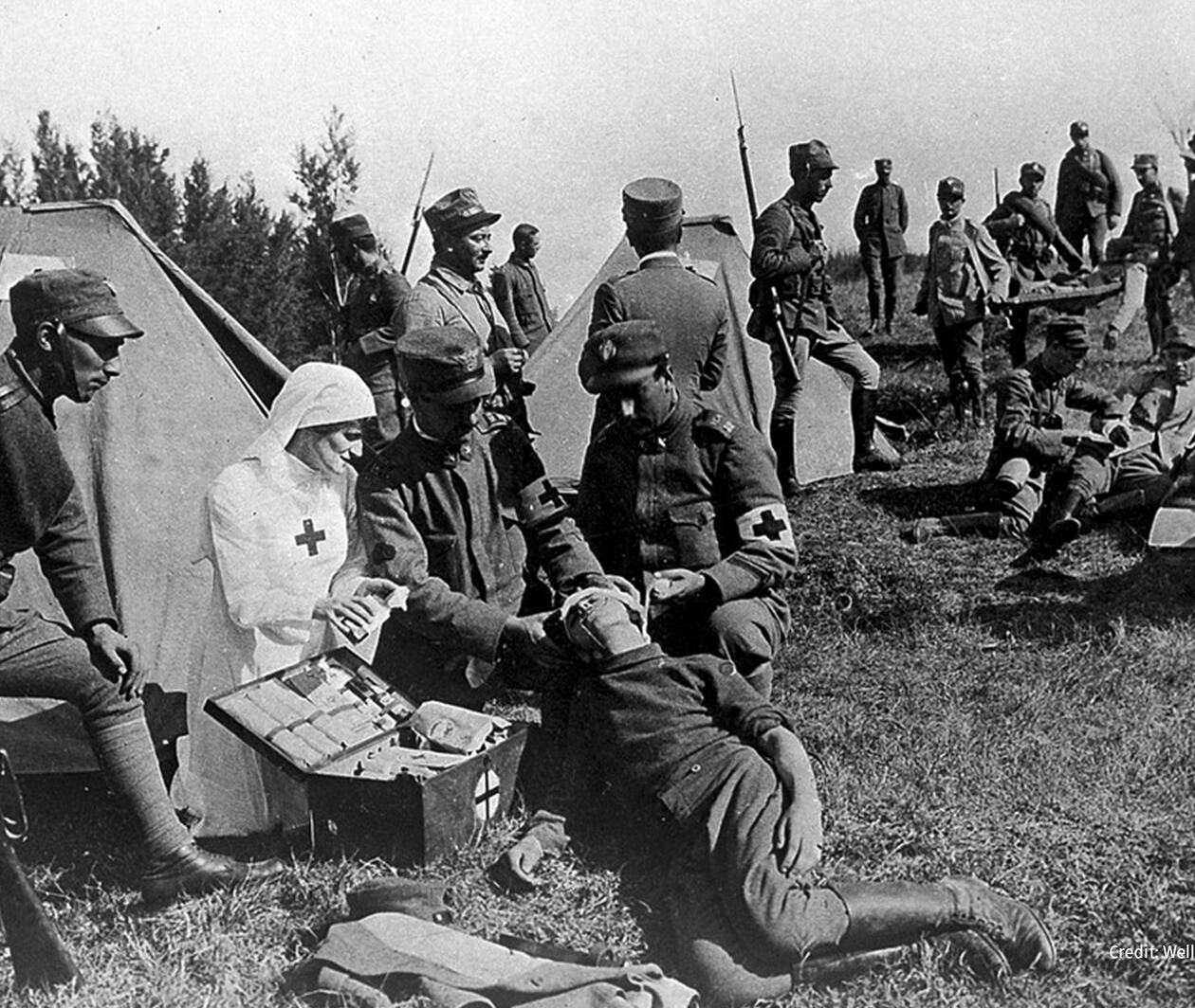 A Red Cross nurse tends to a wounded soldier behind enemy lines