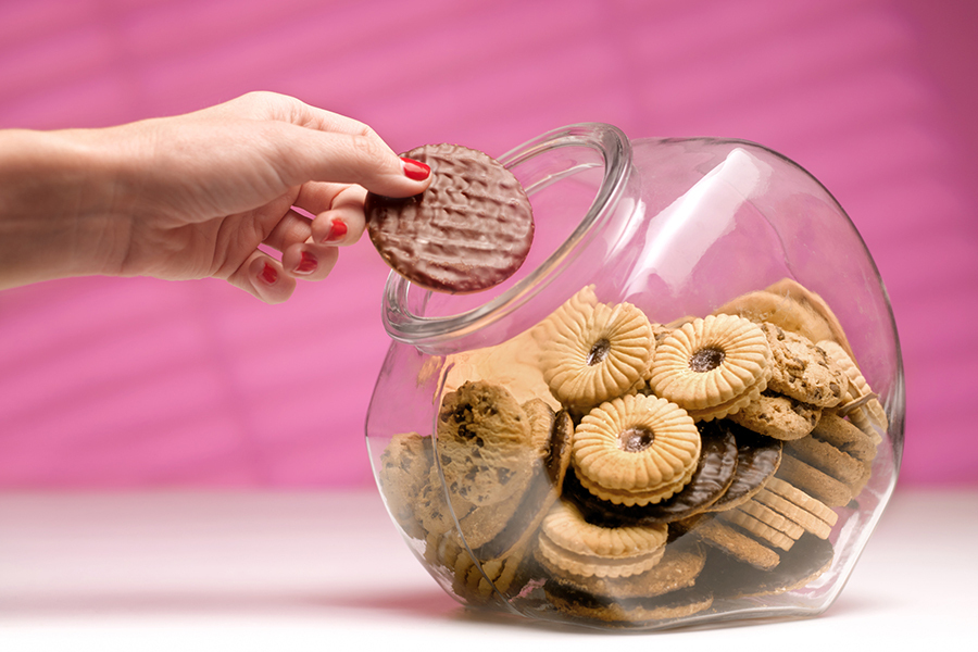 A hand reaching into a biscuit jar