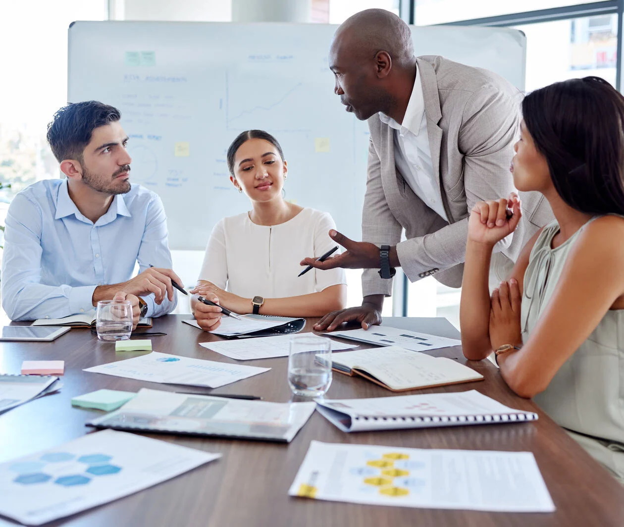 Collegues at a table discussing work surrounded by paper and work