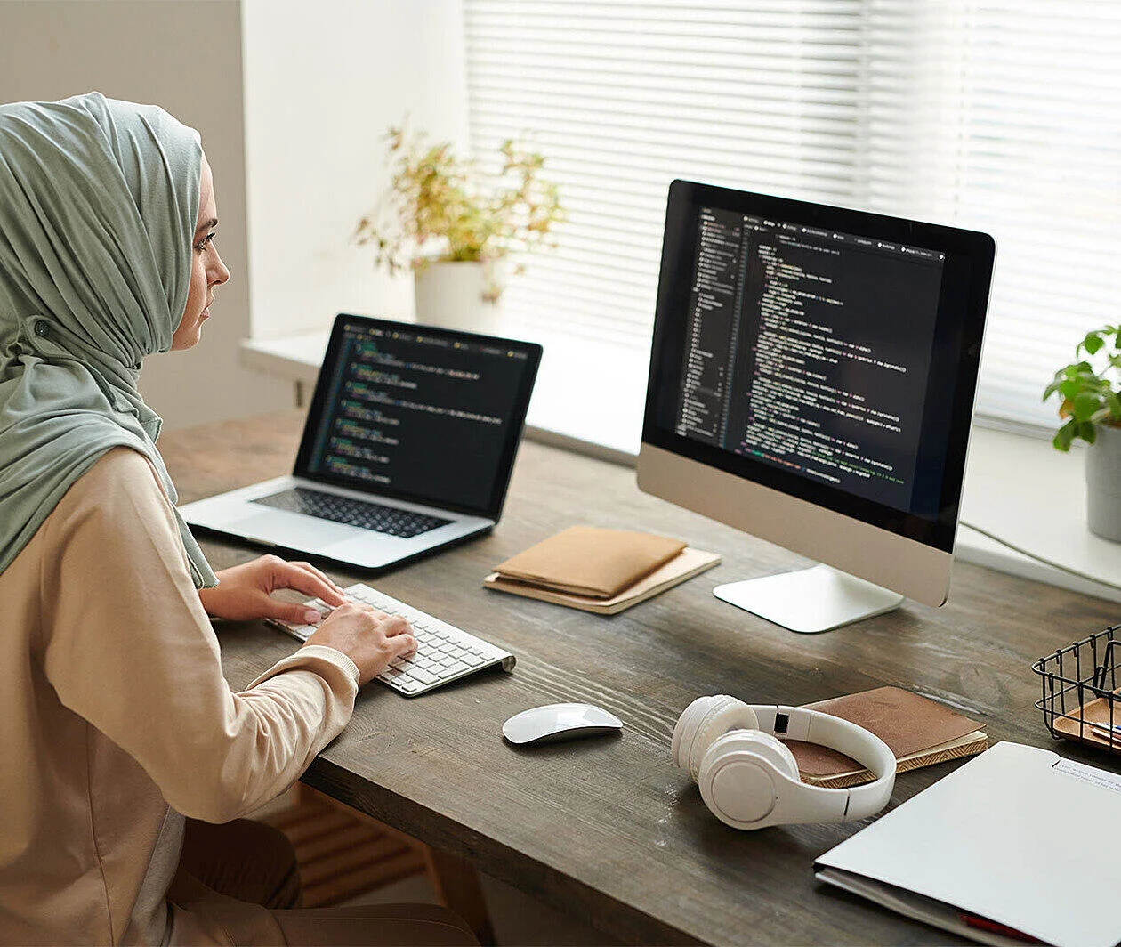 Lady working at two screens that show lines of code on them