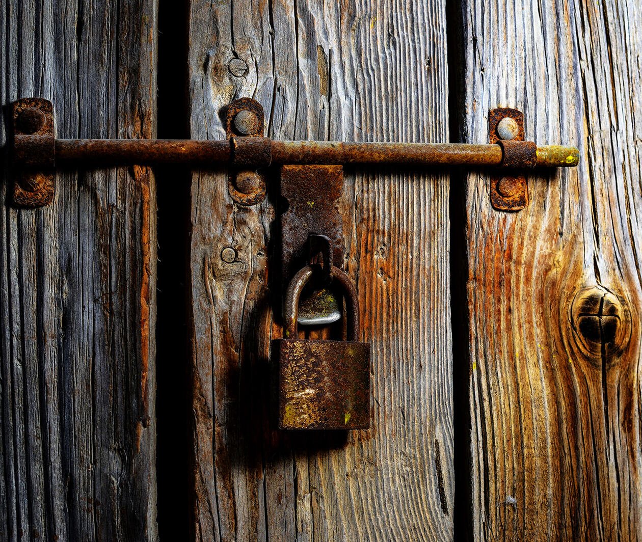 A rusted padlock on rotting timber