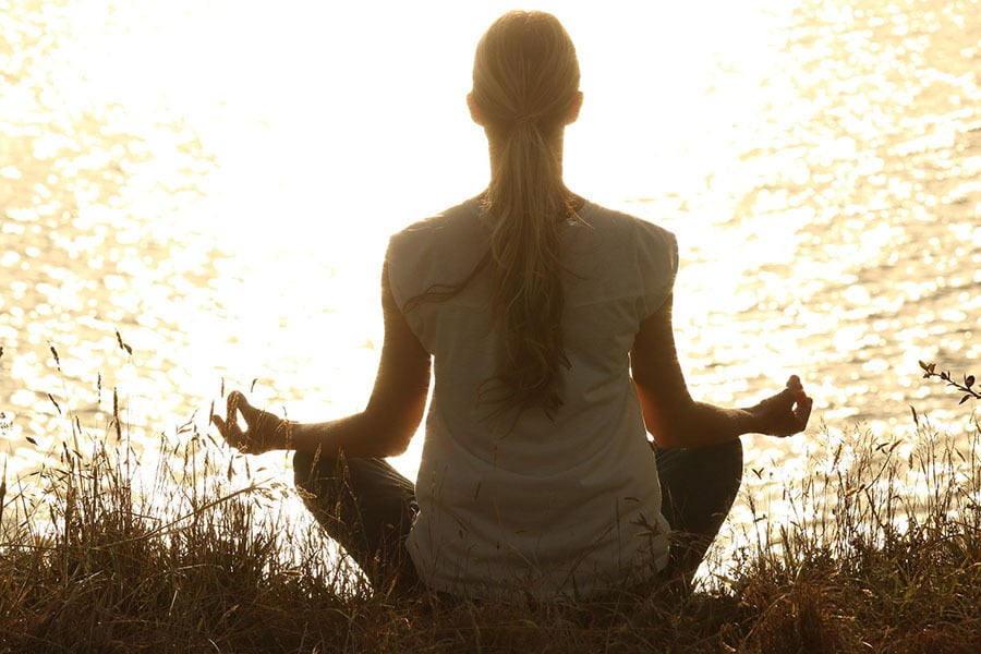 Woman meditating by the water