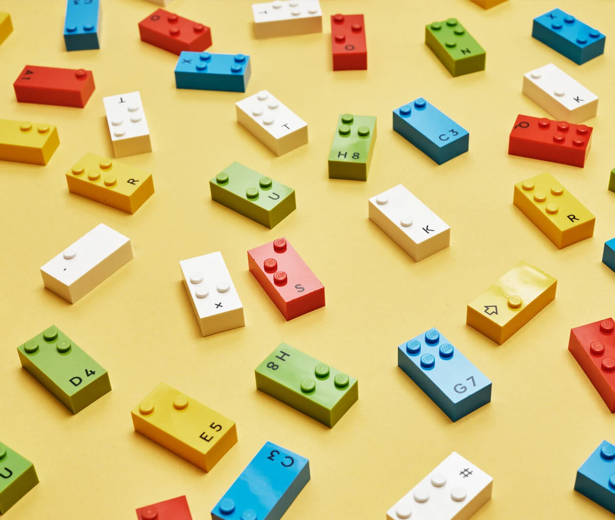 A selection of different LEGO Braille Bricks on a yellow table