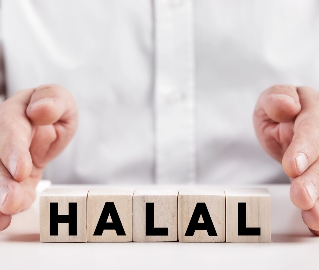 Two hands holding word cubes forming the word 'Halal'.