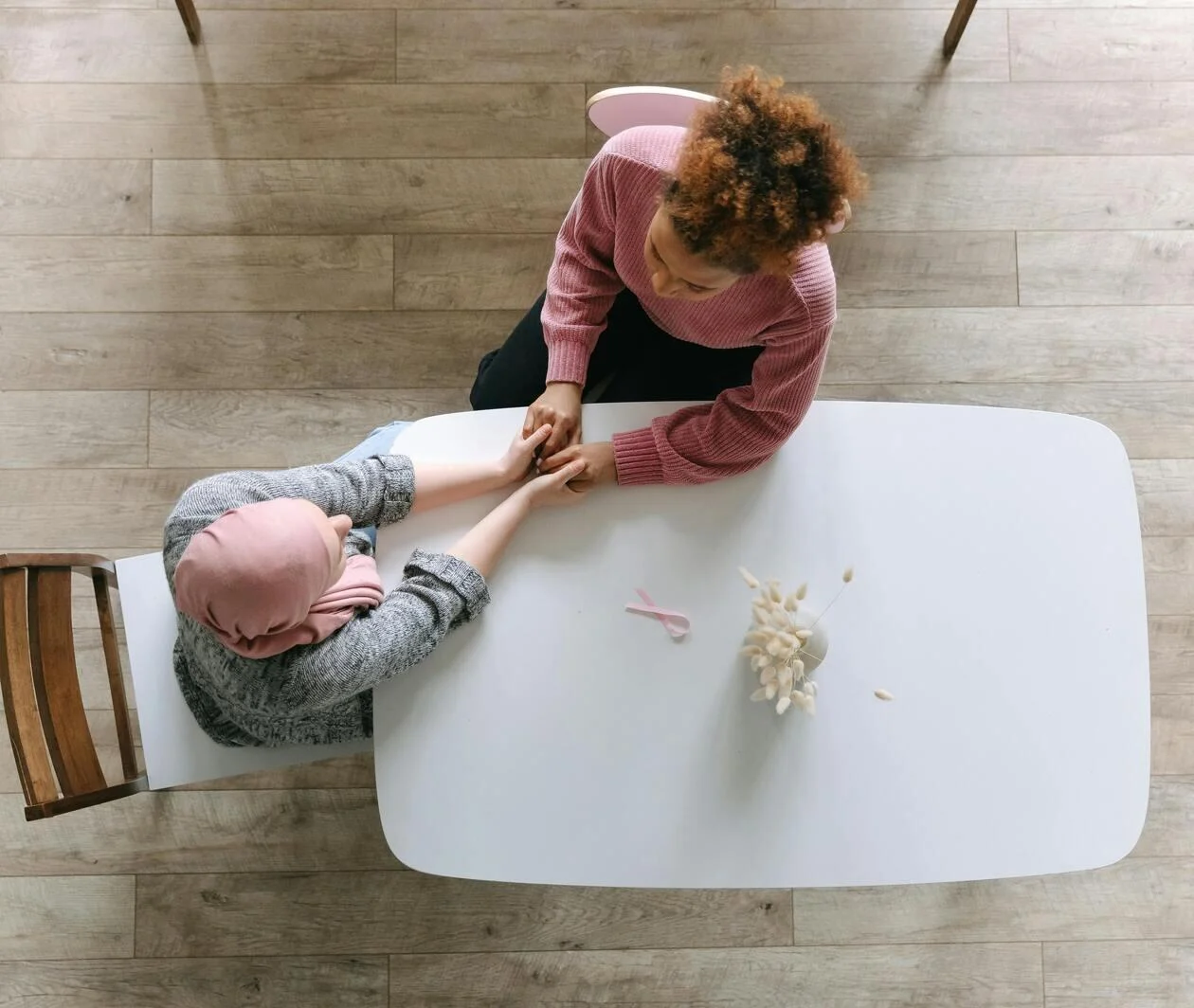 An aerial photo of two woman at a table holding hands.