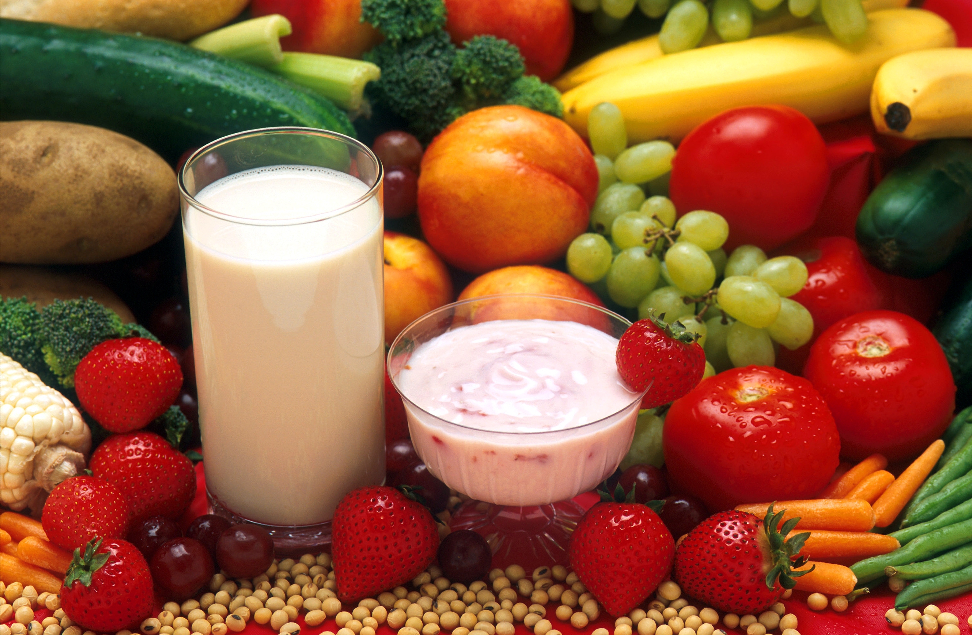 A platter of fruit and vegetables with a glass of milk and bowl of yogurt