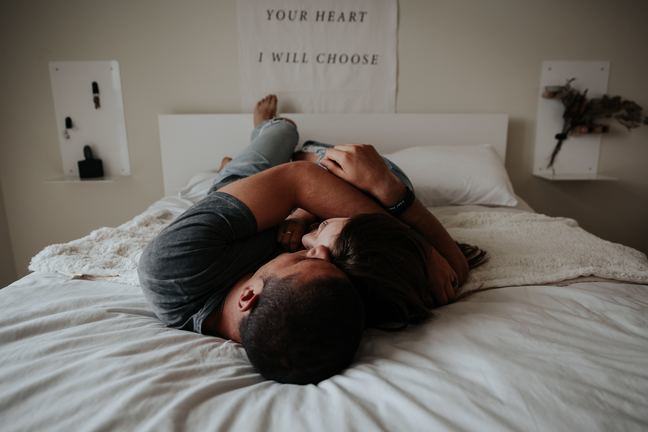 Vrouw en man in omhelzing liggend op bed