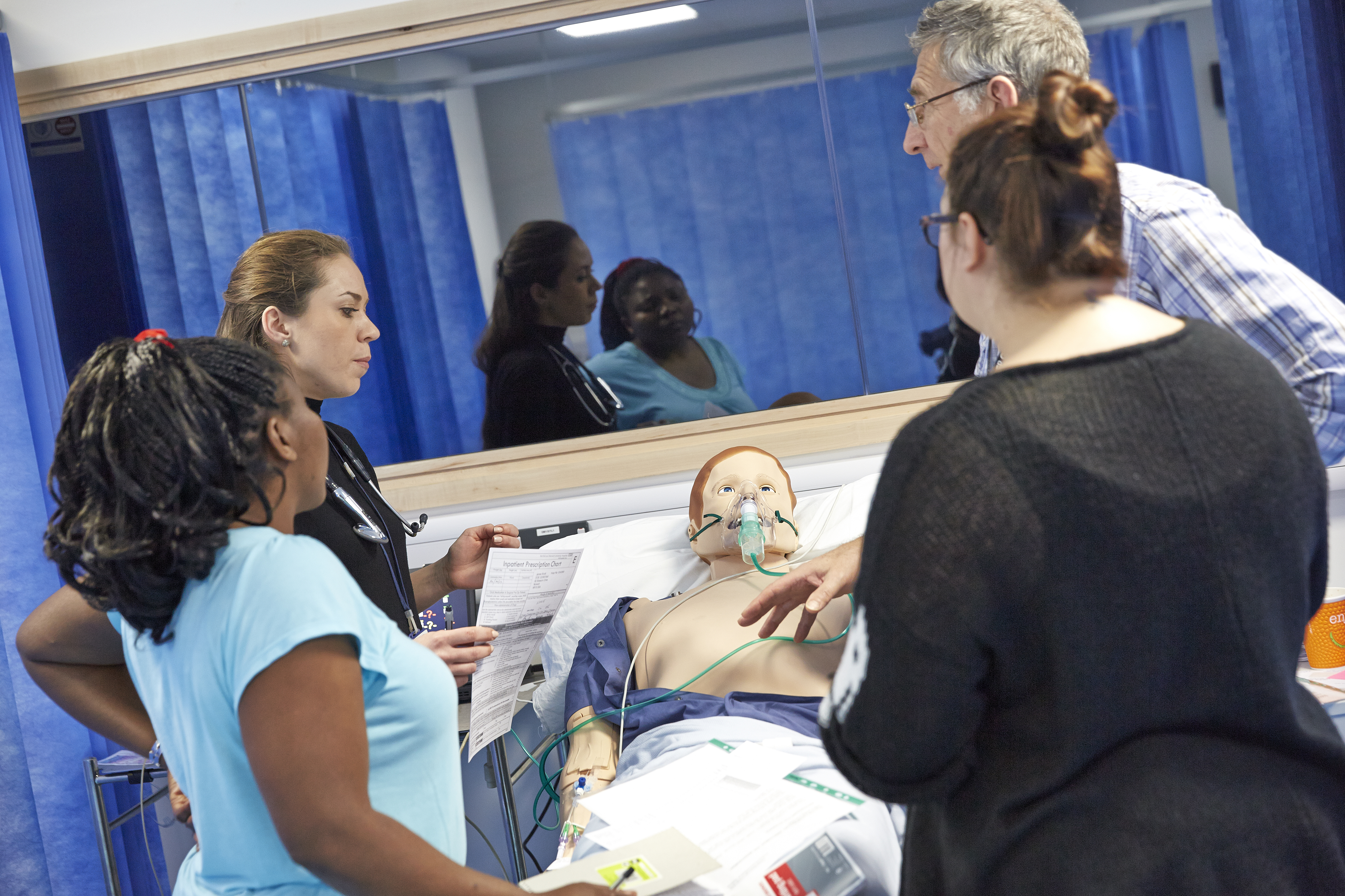 Students gathered around a medical dummy in a bed