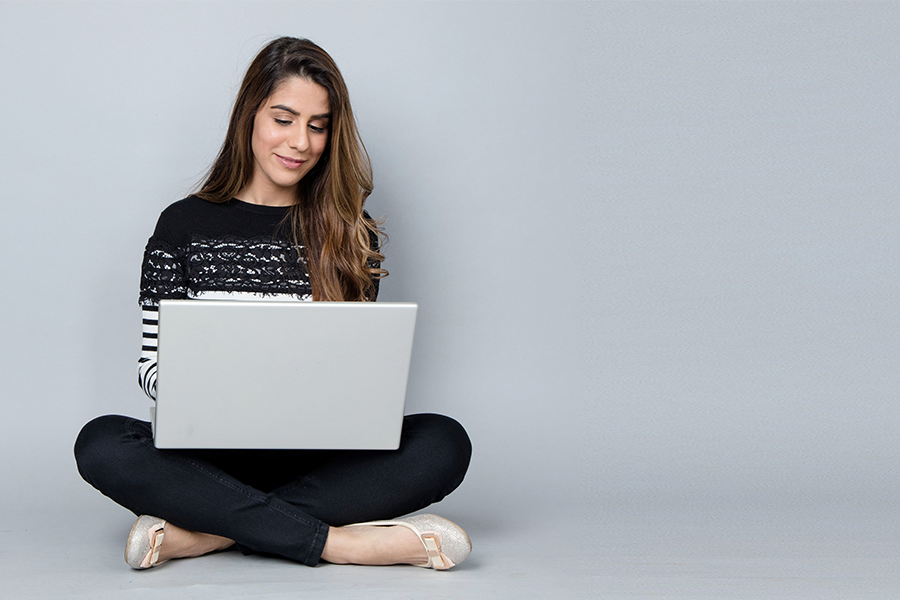 Woman sitting on the floor, with her legs crossed, using a laptop