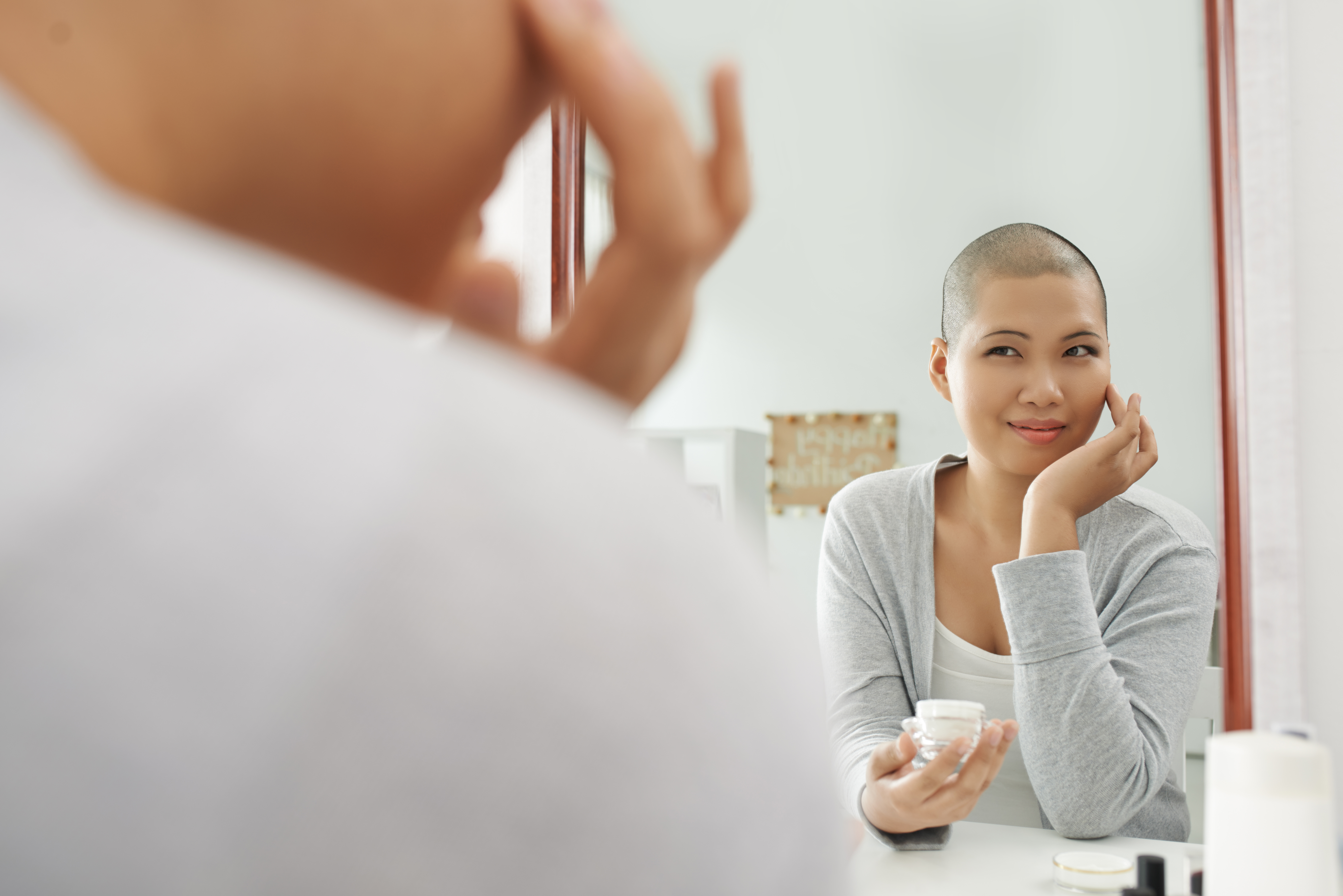 Lady stands in front of mirror applying make up in preparation for her first day at work.