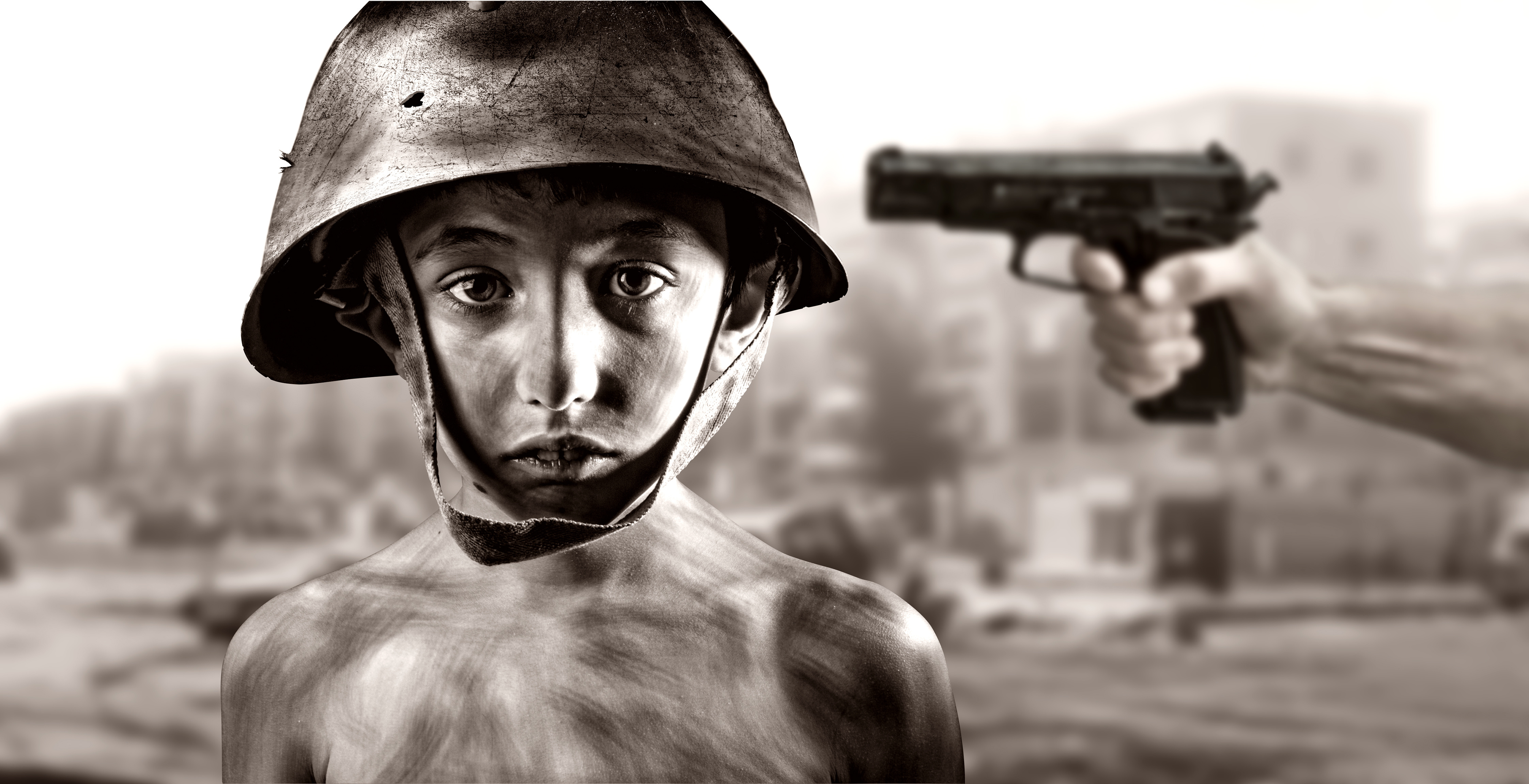 black and white close-up of a child soldier with a gun pointed at his shoulder