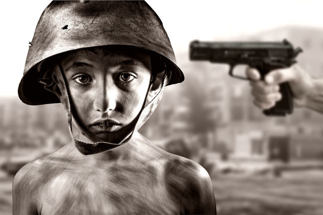 black and white close-up of a child soldier with a gun pointed at his shoulder