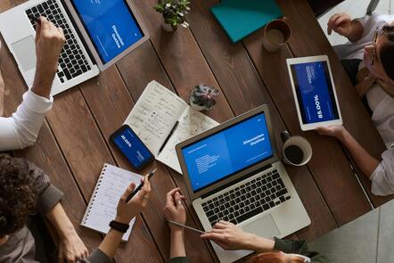 Top down view of people round a table with laptops discussing a topic