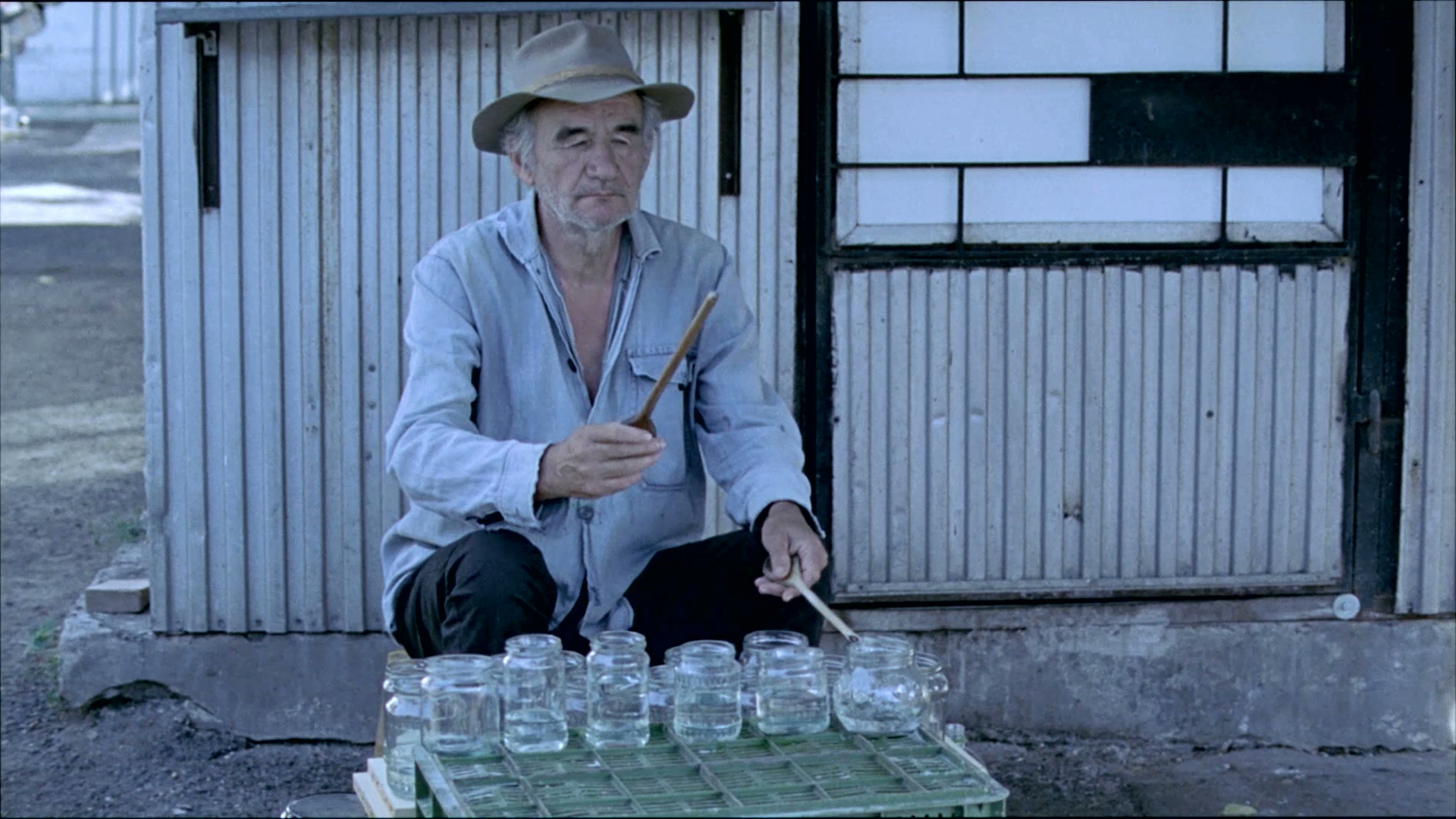 Old man character from the film *Szalontudo* playing the jam jars with drum sticks